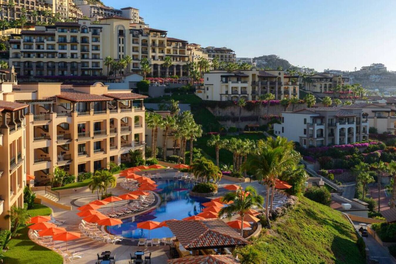 Ein Resort mit einem zentralen Pool, mehreren Balkonen und üppiger Bepflanzung.