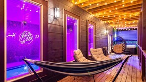 A wooden deck with a hammock, chairs, and a pool area with purple lighting. - Heated Pool, Arcades, Hot Tub, Sauna, Dolly Vibes (sevierville)
