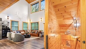 A spacious living room with a wooden ceiling, a large deer skull wall decoration, and a sign reading "TO THE DISCO". - Heated Pool, Arcades, Hot Tub, Sauna, Dolly Vibes (sevierville)