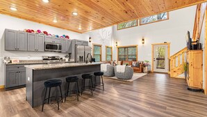 A spacious kitchen with a large island, bar stools, and a wooden ceiling. - Heated Pool, Arcades, Hot Tub, Sauna, Dolly Vibes (sevierville)