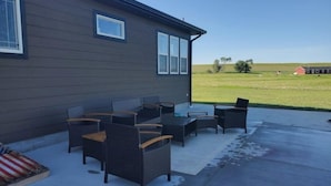 An outdoor patio with wicker furniture and a view of a grassy field. - Angostura lake getaway (Hot Springs)