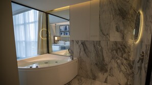 Un baño moderno con una bañera grande, paredes de mármol y un espejo amplio.