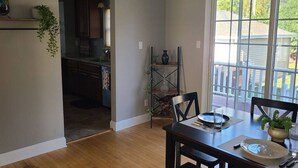 A dining area with a table set for two, a kitchen in the background, and a view through a glass door. - Amazing 3 bedroom home, perfect for families! (Glendale)