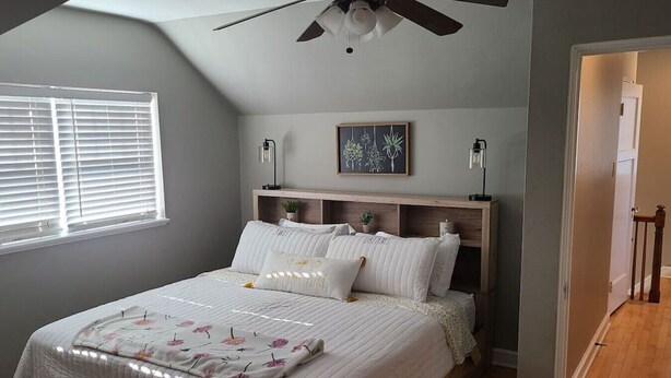 A bedroom with a bed, a ceiling fan, a window with blinds, a framed artwork on the wall, and a door leading to another room. - Amazing 3 bedroom home, perfect for families! (Glendale)