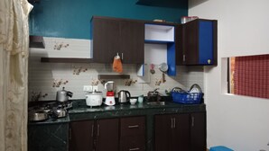 Een keuken met donkere houten kasten, een wit aanrechtblad en een blauwe wand.