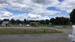 An outdoor parking area with a playground, a small building, and a car. - RV hookup in small Montana town next to city park Address: 202 Oak (Plains)