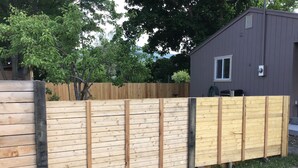 A wooden fence with a metal gate, a wooden deck, and a building with a window and a door. - RV hookup in small Montana town next to city park Address: 202 Oak (Plains)