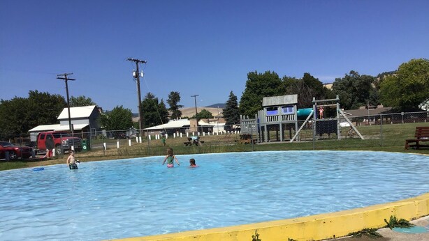 A swimming pool with a yellow safety border, a turtle mural on the ground, and a playground in the background. - RV hookup in small Montana town next to city park Address: 202 Oak (Plains)