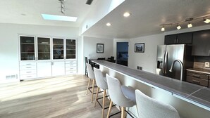 Une cuisine moderne avec un coin bar, un plancher en bois et un meuble intégré doté de portes en verre.