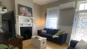 Un salon avec une cheminée, un ventilateur de plafond, un canapé, une table basse et un téléviseur.