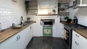 Une cuisine moderne avec des armoires blanches, un four vert, une cuisinière noire et une lucarne.