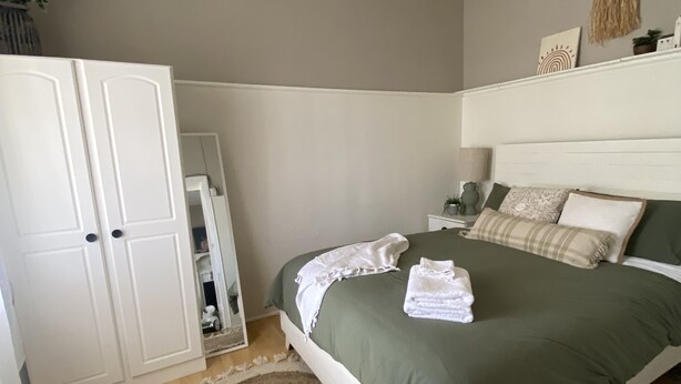 Une chambre à coucher avec un lit, un ventilateur de plafond, une armoire et un tapis rond.