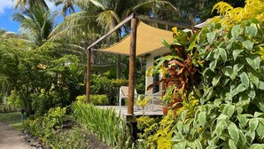 A covered outdoor seating area with a wooden structure, surrounded by lush tropical vegetation and palm trees. - Studio with Ocean View (Somosomo)