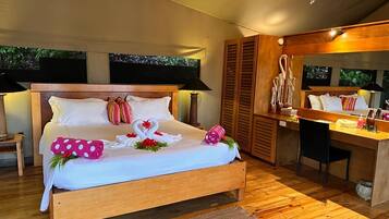 A wooden bed with a white bedspread, two pillows, a decorative swan, and a mirror above the bed.