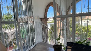 Een balkon met een laptop, potplanten en uitzicht op de omgeving.