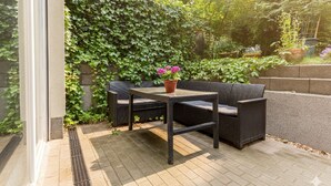 A patio with a table and two chairs, surrounded by a brick wall and lush greenery. - Central and quiet design apartment Berlin (Berlin)