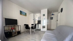 Um espaço compacto com sofá, televisão, mesa de jantar com cadeiras e uma kitchenette.