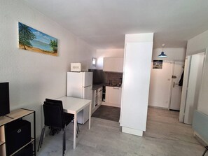 Eine kompakte Küche mit Kühlschrank, einem Essbereich mit Tisch und Stühlen sowie einer kleinen Kochinsel.