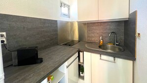 Uma cozinha compacta com fogão embutido, pia e armários brancos.