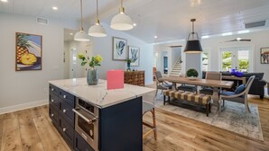 Een moderne keuken met een groot keukenblok, houten kastjes en hanglampen.