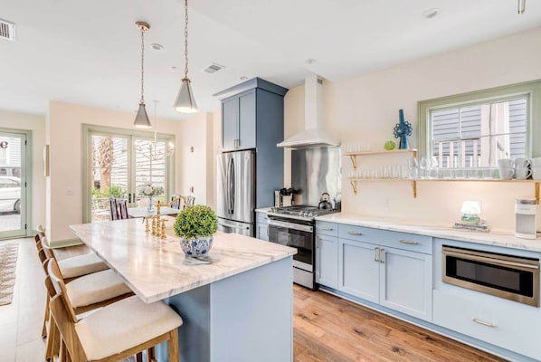 A modern kitchen with a central island, stainless steel appliances, and light blue cabinetry.