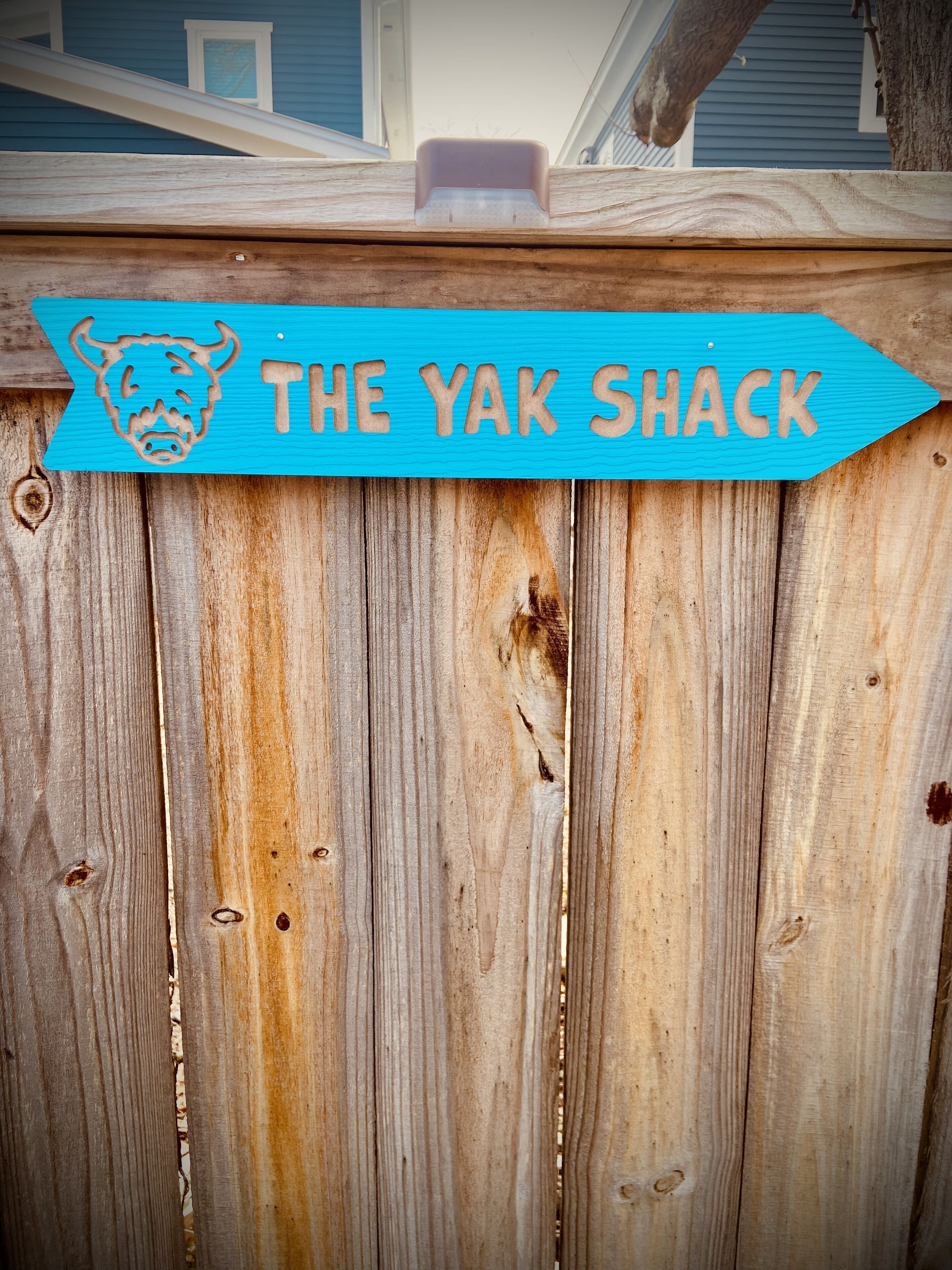 Ett trästaket med en skylt som visar texten ”THE YAK SHACK” och en utskuren bild av ett tjurhuvud.