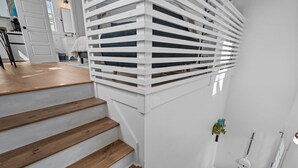 A staircase with wooden steps and white railings, leading to a landing with a door and a small plant. - The Yak Shack: Carriage House in Historic District - 4 blocks from Riverwalk (Wilmington)