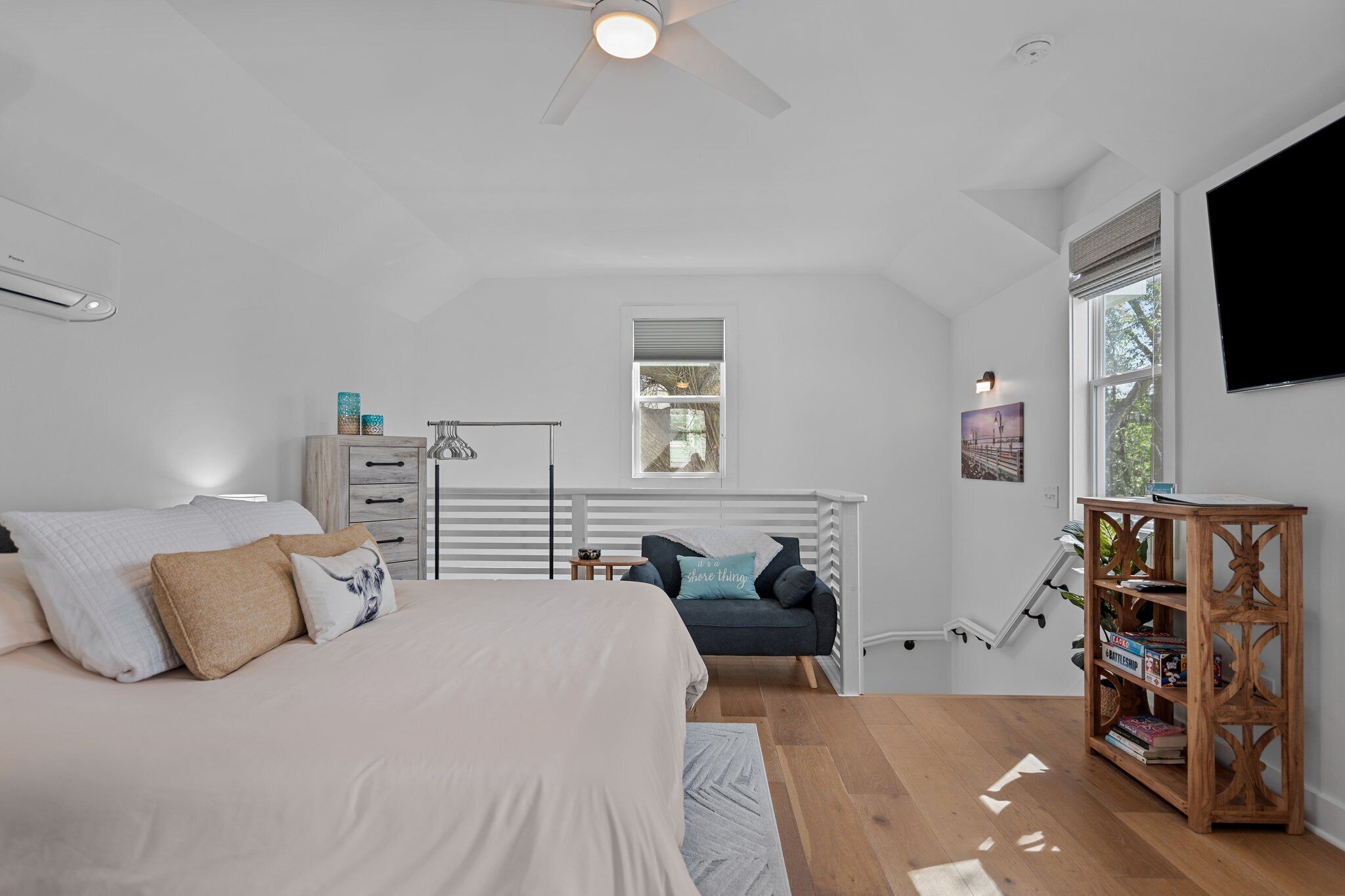 A bedroom with a bed, a desk, a chair, a bookshelf, and a TV.