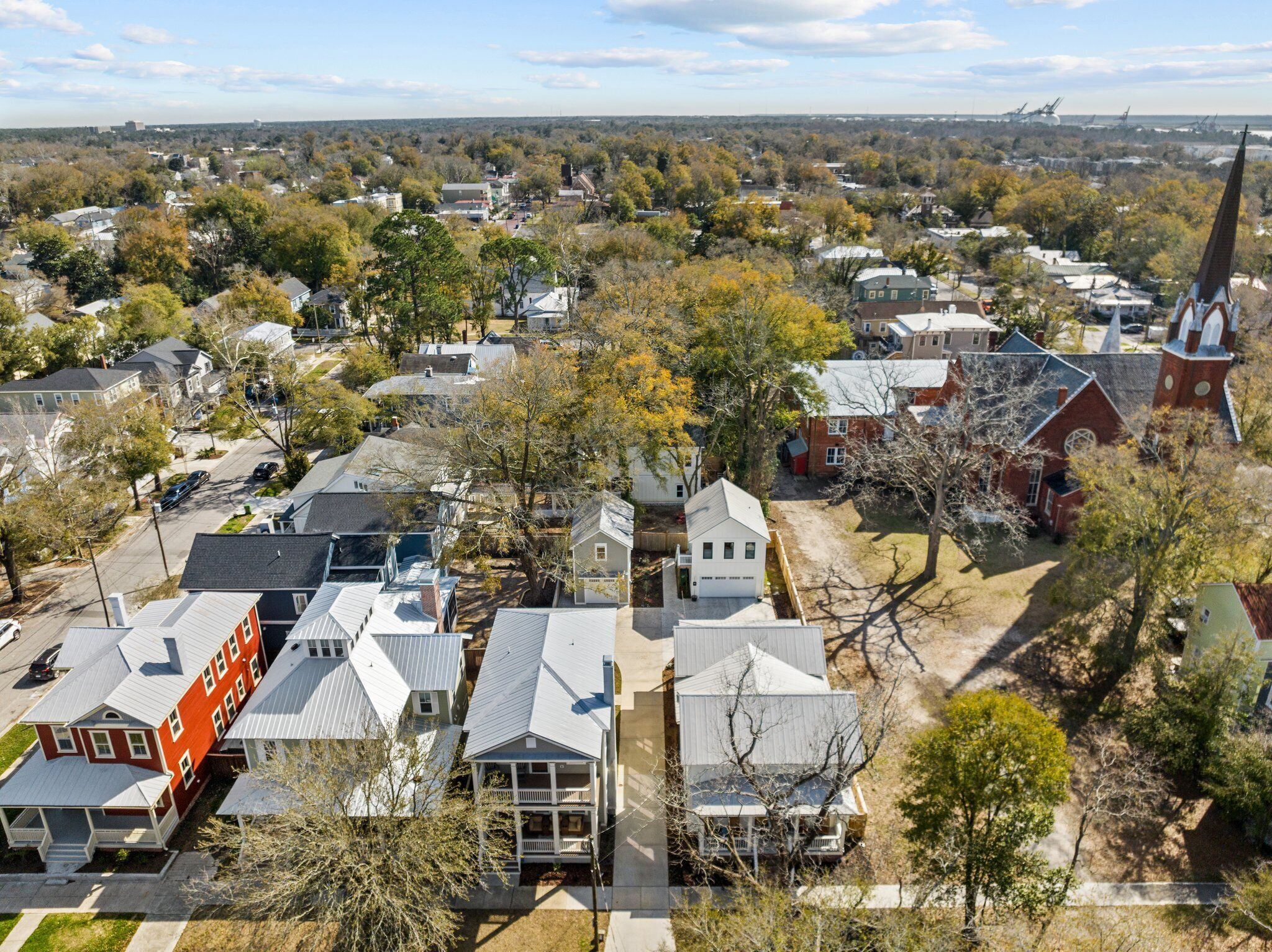 A residential area with houses, a church, and a large building in the distance.