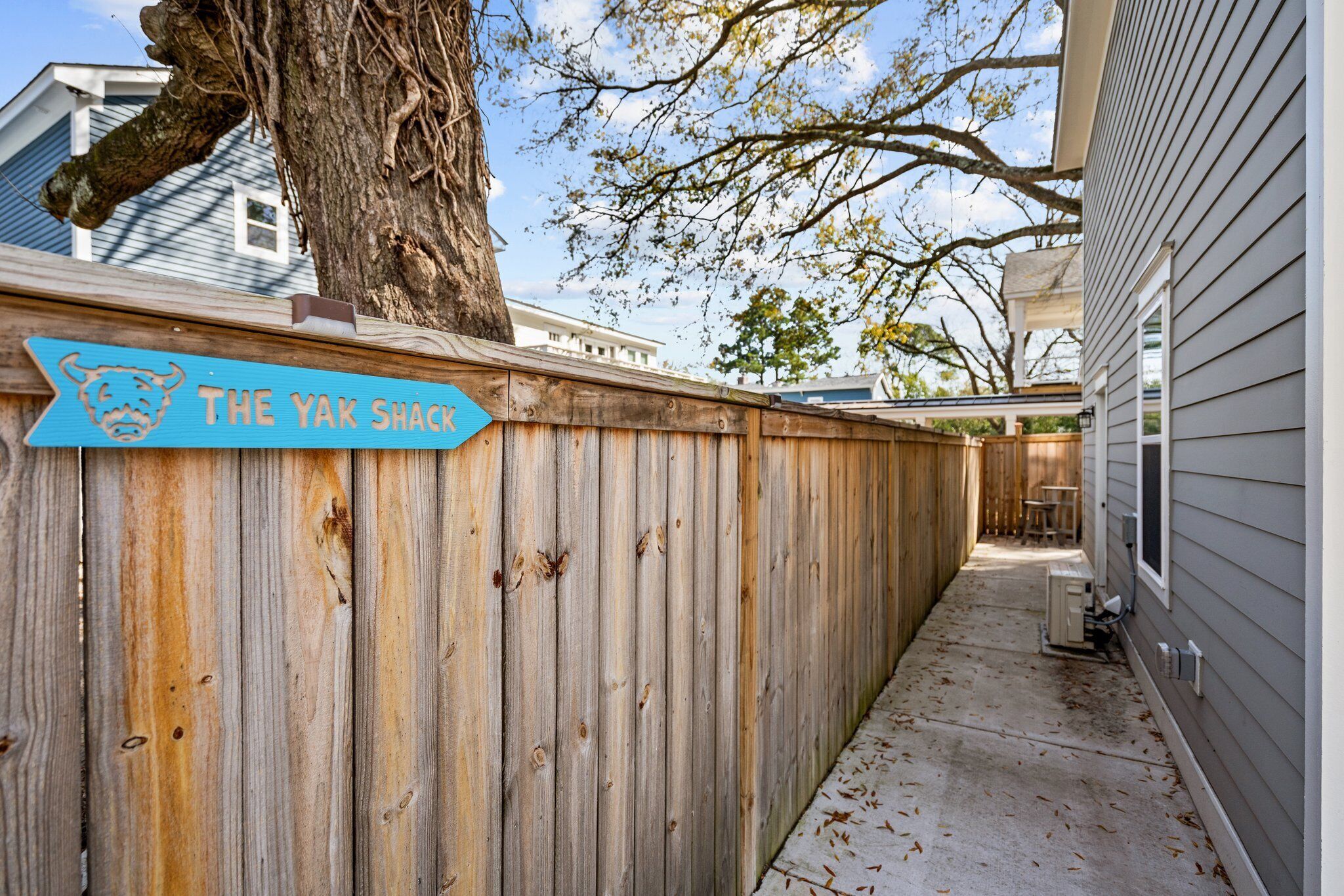 A wooden fence with a sign reading "The Yak Shack" and a tree behind it.