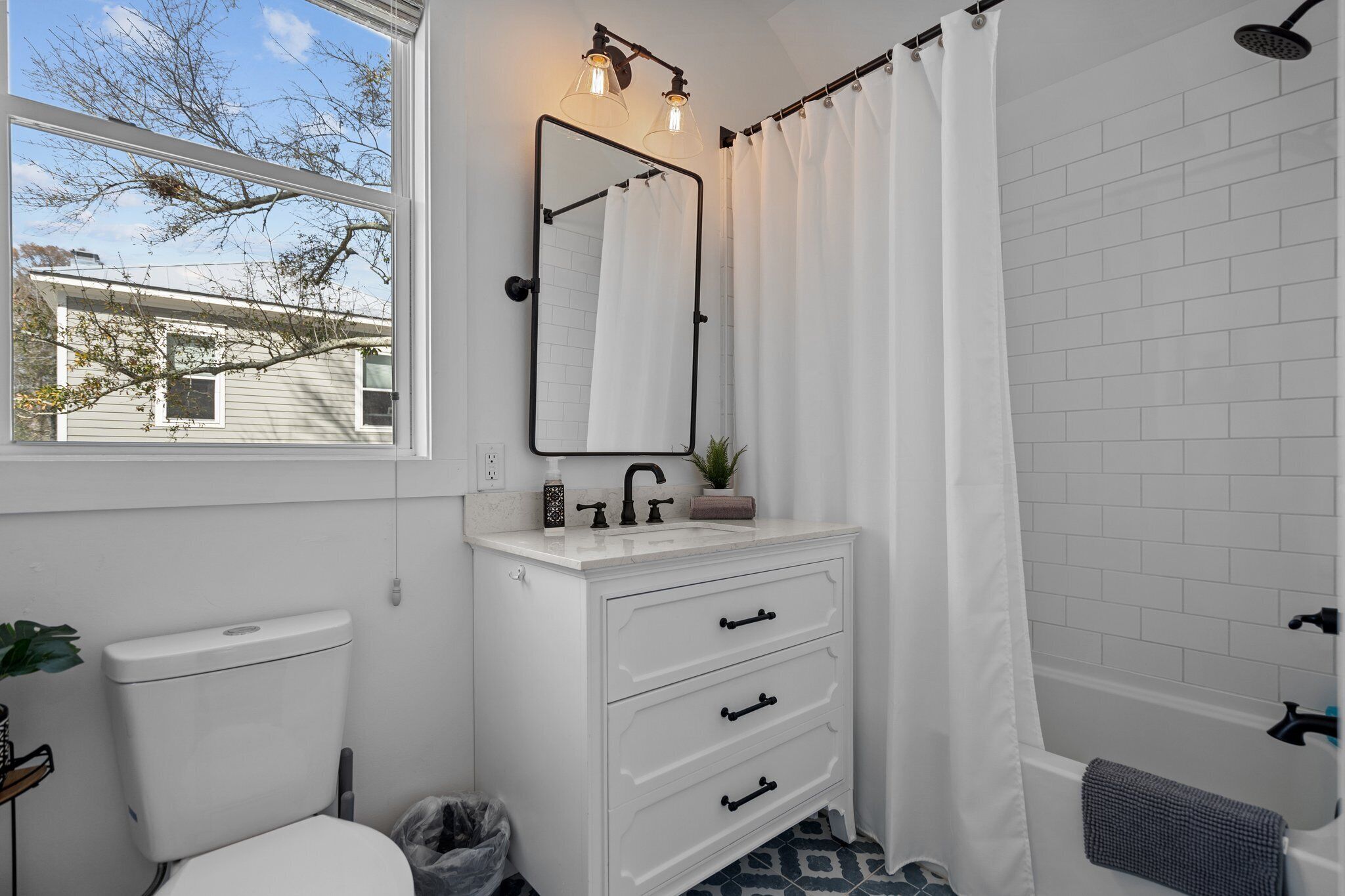A bathroom with a white sink, a mirror, a toilet, and a shower curtain.