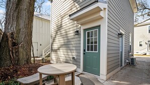 A house with a green door, a covered patio with a round table and benches, and a tree in the background. - The Yak Shack: Carriage House in Historic District - 4 blocks from Riverwalk (Wilmington)