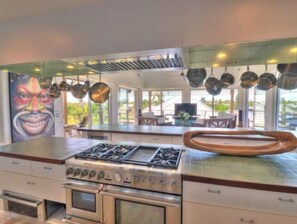 A modern kitchen with stainless steel appliances, a large island, and a mural on the wall.