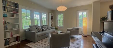 A modern living room with a grey sofa, a coffee table, and a bookshelf.