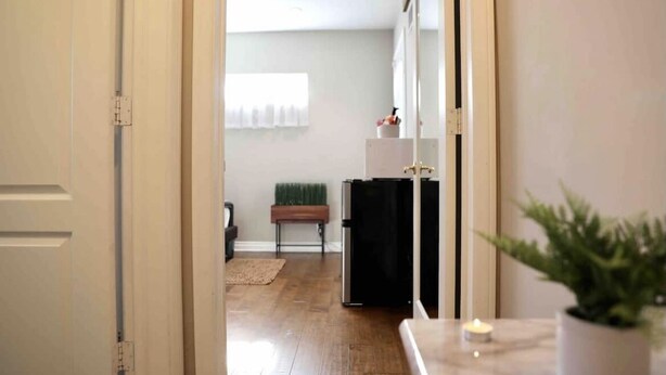 A hallway with a wooden floor, a bench, a refrigerator, and a potted plant. - Bright and Charming Guest House (10 mins from LAX) (Los Angeles)