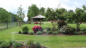 A well-maintained garden with a gazebo, various shrubs, and a fenced area. - Haffhaus 1 - Haffhaus (Garz)