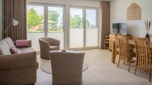 A spacious living area with a sofa, armchair, and dining table with chairs. - Haffhaus 1 - Haffhaus (Garz)