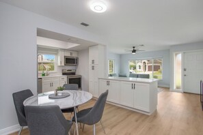 A modern kitchen with white cabinets, a central island, and a dining area with a round table and chairs. - Heated Pool & Spa – Near the Beach, Bikes Included (Naples)