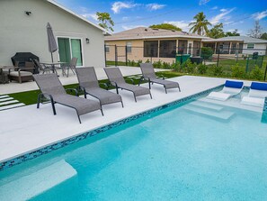 A swimming pool with lounge chairs and a patio area. - Heated Pool & Spa – Near the Beach, Bikes Included (Naples)