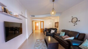 Ein modernes Wohnzimmer mit Flachbildfernseher, Ledersofa und einem gemusterten Teppich.