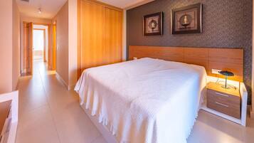 Un cuarto de hotel con una cama grande, un cabecero de madera, una mesita de noche con lámpara y dos cuadros enmarcados en la pared.