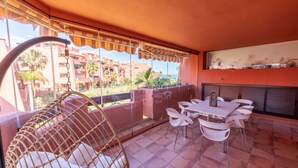 Ein Balkon mit Korbmöbeln, einem Tisch mit Stühlen und Blick auf eine Wohngegend.