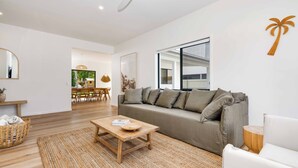 Una sala de estar moderna con un sofá gris, una mesa de centro de madera y un ventanal grande.