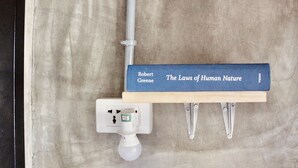A book titled 'The Laws of Human Nature' by Robert Greene on a shelf. - Hangover Hostel (Moalboal)