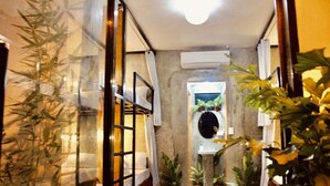 A hallway with a glass door, potted plants, and a window at the end. - Hangover Hostel (Moalboal)