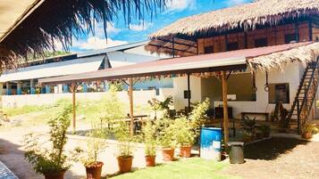 A building with a thatched roof and a covered patio area with potted plants.