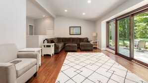Una sala de estar moderna con un sofá modular, una mesita blanca y un ventanal con vistas a zonas verdes.