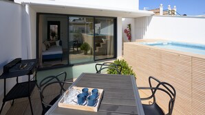 Uma área externa moderna com área de estar, mesa e cadeiras, uma piscina pequena e um quarto com vidro, com cama e sofá.
