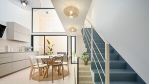 Uma cozinha moderna com área de jantar, escada e vista para a sala de estar.