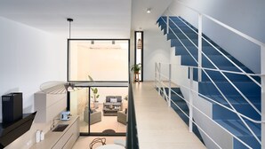 Interior moderno com escada, área de cozinha e espaço de estar com vista.